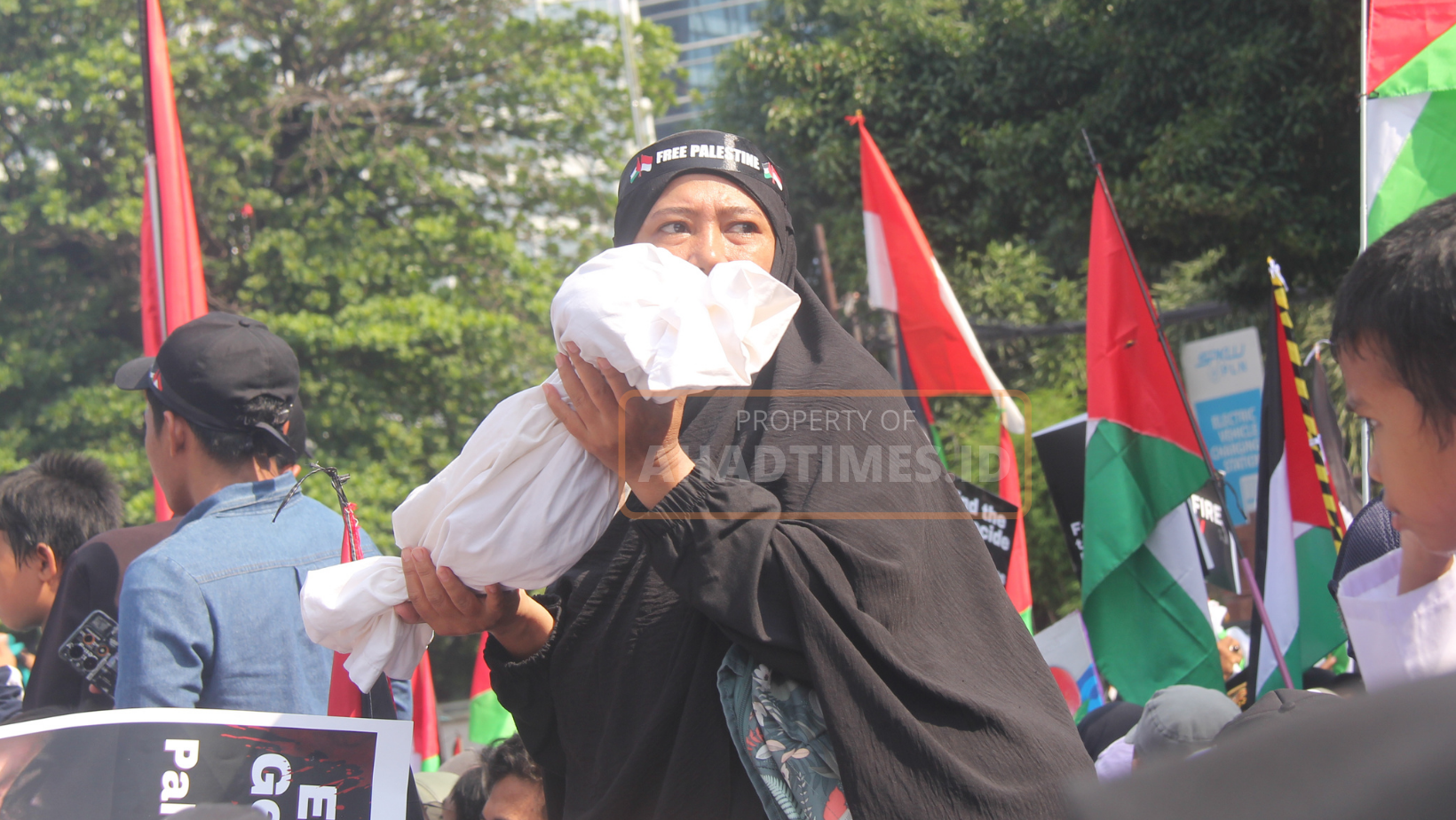 Seorang ibu mengenakan pakaian muslimah, salah satu peserta aksi bela Palestina memegang replika jenazah bayi sebagai simbol kekejaman zionis Israel yang membantai puluhan ribu anak-anak Palestina.